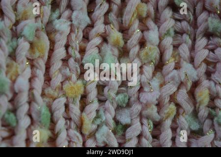 Hand weaving, knitting. A beautiful patterned background is knitted from pink threads with colored inserts. Stock Photo