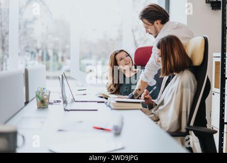 Young employees collaborating in a modern office. Discussing project solutions with happy and successful results. Stock Photo