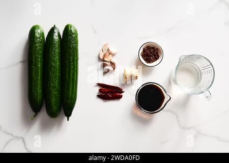 Preserved and marinated cucumbers in asian or Chinese style with soy sauce, garlic. Also includes ginger, chilli and other spices. White marble Stock Photo