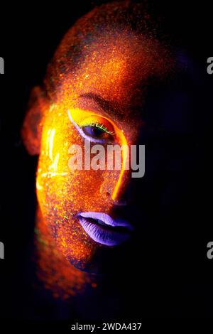 Portrait, fantasy and creative with neon woman on black background for makeup, glitter or colorful glow. Face, art and beauty with confident young Stock Photo