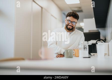 Male person enjoying his coffee during break at work. He is sitting at the kitchen. Stock Photo