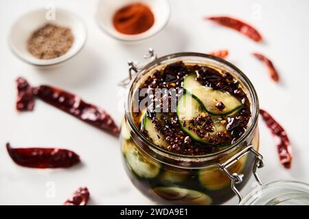 Preserved and marinated cucumbers in jars in asian or Chinese style with soy sauce, garlic. Also includes ginger, chilli and other spices. White Stock Photo