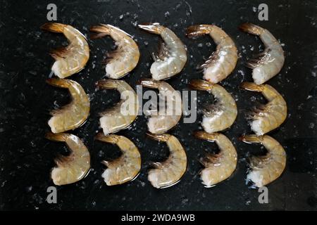 Healthy organic raw tiger shrimps set on black background, top view flat lay. Stock Photo