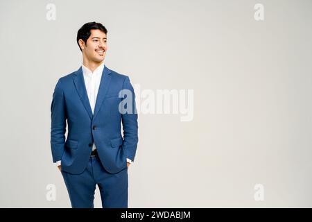 Young handsome male office employee dressed in a sharp blue suit standing with hands in pockets isolated on white, the ideal image of a successful young professional. Stock Photo