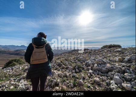 Woman in her 50s with a small backpack walking among the stones of Torcal de Antequera (Spain) on a sunny winter morning Stock Photo