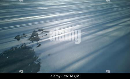Snowdrift background with shadow of trees, tree shadows lie on the ice covered by snow, aerial low angle view. Stock Photo