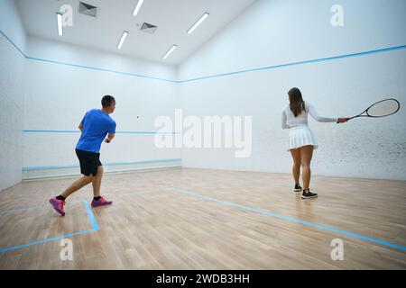 Woman athlete refines squash hitting techniques under man instructor's guidance Stock Photo
