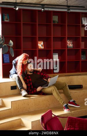 Male and female fellow students working on project on laptop Stock Photo