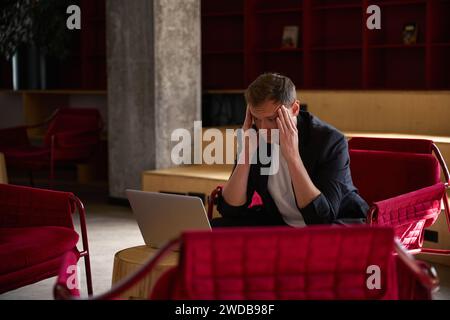 Tired businessman feeling headache working on project on laptop Stock Photo