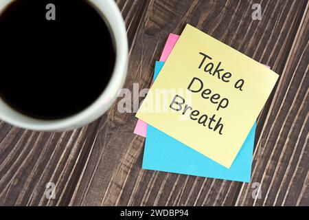 Take a deep breath text on adhesive note and cup of coffee Stock Photo