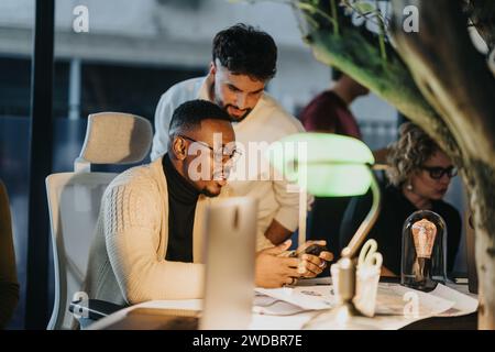 Diverse business professionals collaborating on strategies for growth, analyzing statistics and sales opportunities late into the evening. Stock Photo
