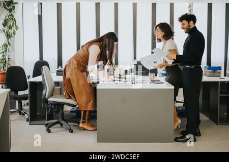 Team of three professionals collaborating with papers in a modern office, conveying teamwork and productivity Stock Photo