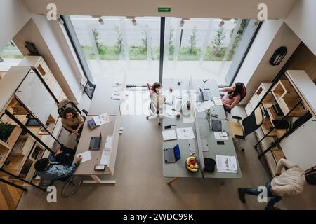 A top view of a bustling modern office space with a diverse team of professionals collaborating at their desks on various projects. Stock Photo
