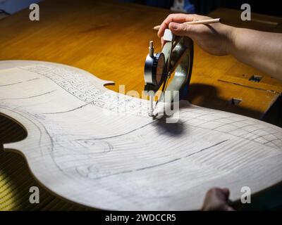 Close up of Stringed instrument maker master luthier hand proceed with graduation work in progress violon cello back plate, using planes, thickness Stock Photo