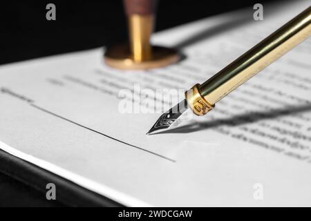 Signing document with fountain pen at dark table, closeup. Notary contract Stock Photo