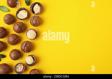 Tasty Macadamia nuts on yellow background, flat lay. Space for text Stock Photo