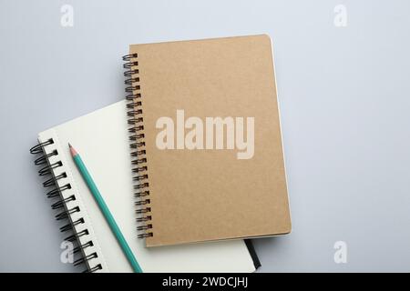Notebooks and pencil on light grey background, top view Stock Photo