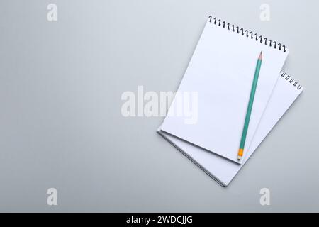 Notebooks and pencil on light grey background, top view. Space for text Stock Photo