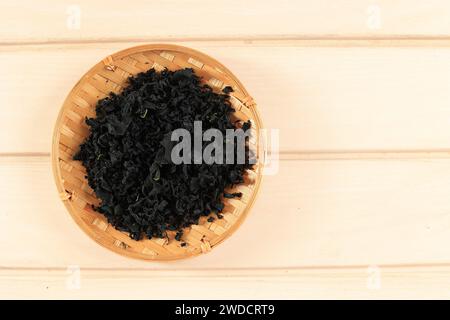 Dried Laminaria Kelp Seaweed on Bamboo Plate. Dried Laminaria, Konbu, Alga, Wakame. Top View Stock Photo