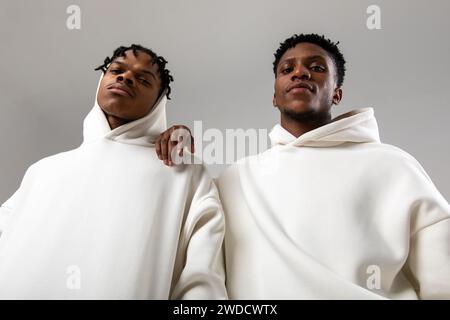 2 African American guys in white hoodies posing on a white background Stock Photo