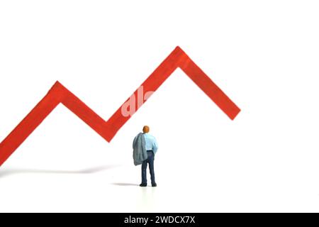 Miniature tiny people toy figure photography. Investment failure and loss concept. A businessman standing in front of red bar declining graph. Isolate Stock Photo