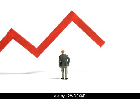 Miniature tiny people toy figure photography. Investment failure and loss concept. A businessman standing in front of red bar declining graph. Isolate Stock Photo