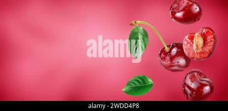 red cherries and slice with water drops flying in the air stream on pink background Stock Photo