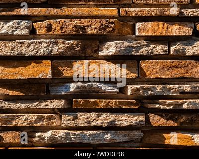The masonry wall are made of gray wild flat stone. Side natural sunlight. Copy space. Close-up. Stock Photo
