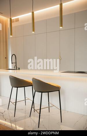 Minimalistic light interior of modern kitchen with island and high bar chairs Stock Photo