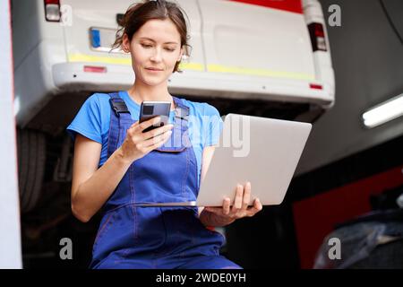 Woman auto mechanic with a laptop in car repair shop Stock Photo