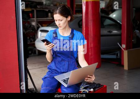 Female auto mechanic with a laptop in car repair shop Stock Photo