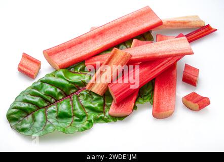 Red rhubarb stems' cuts over rhubarb leaves isolated on white background. Stock Photo