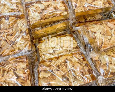 Bugie (Lies) or frappe or chiacchere or angel wings. Traditional italian carnival dessert in golden packages displayed for sale in market Stock Photo