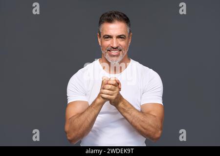 Happy fit sporty older man personal trainer showing support isolated on gray. Stock Photo