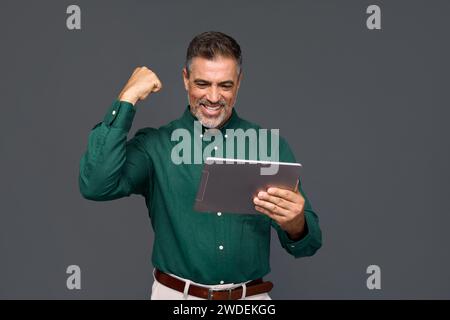 Happy older business man investor looking at digital tablet winning online. Stock Photo