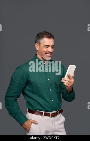 Smiling mature businessman using cell phone isolated on gray background. Stock Photo