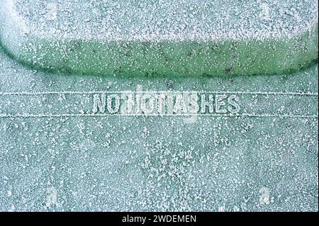 A frozen and frosty No Hot Ashes warning sign on a bin lid Stock Photo