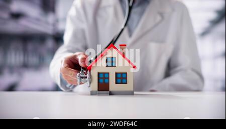 Close-up Of A Doctor's Hand Holding Stethoscope On House Model Stock Photo