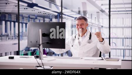Portrait Of Confident Male Doctor Using Computer At Desk In Clinic Stock Photo