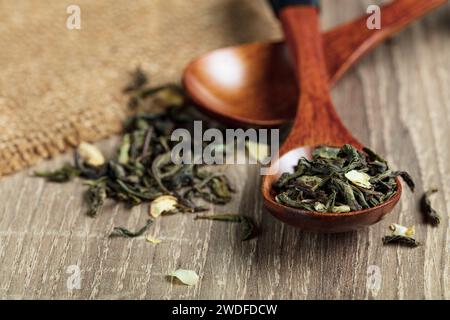 green tea with jasmine leaves in a wooden spoon on wooden background Stock Photo