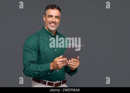 Happy older business man holding digital tablet, isolated on gray, portrait. Stock Photo