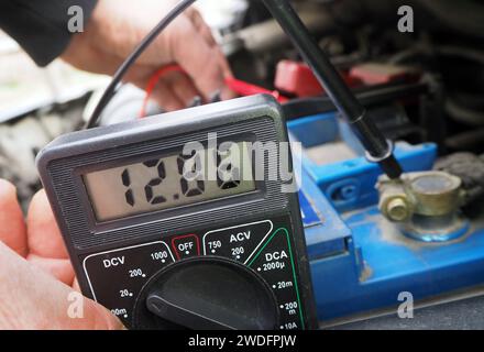 Checking vehicle battery voltage.Battery voltage measurement by using a multimeter. Vehicle accumulator voltage test. Stock Photo