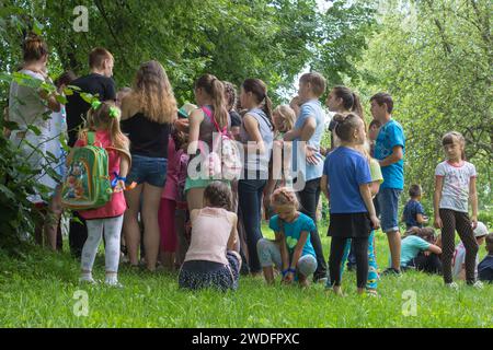 children are standing in a pile in the nature and listen to the teacher, playing children in the camp Stock Photo