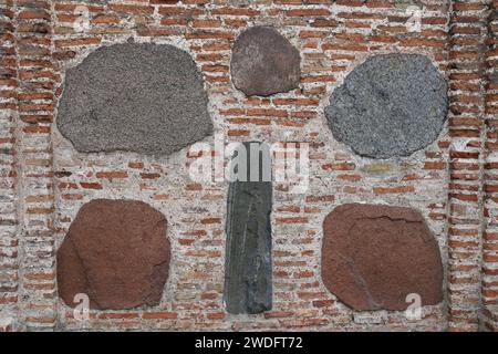 cracked brick wall of rectangular red clay bricks and large stones, cobblestones. The background. Stock Photo