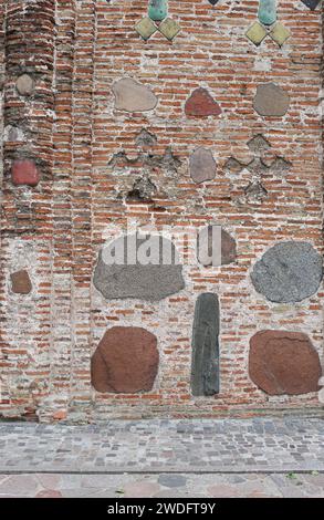 cracked brick wall of rectangular red clay bricks and large stones, cobblestones. The background. Stock Photo
