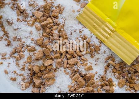 Extreme closeup of sugar and coffee granules from bag of coffee mix poured into a small bowl with end of bag in right corner Stock Photo