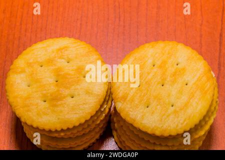 Closeup of two stacks of round butter crackers on brown wood grain background Stock Photo