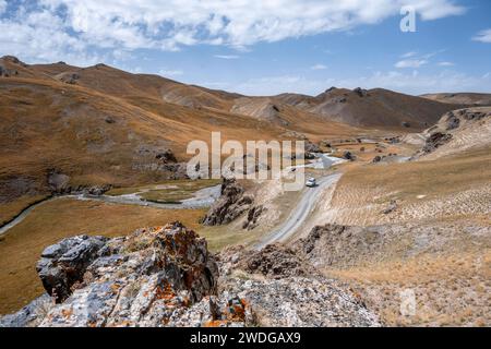Off-road vehicle on a road, track between hills with yellow grass, Kol Suu river winds through a mountain valley, Naryn province, Kyrgyzstan Stock Photo