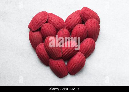 Red velvet madeleines on a marble tray shaped like a heart, red madeleines cake or cookies for valentines Stock Photo