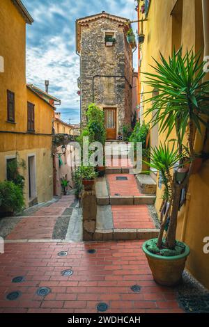 Amazing narrow street view with orderly old colorful houses decorated with green ornamental plants, Menton, Provence Alpes Cote d Azur, France, Europe Stock Photo